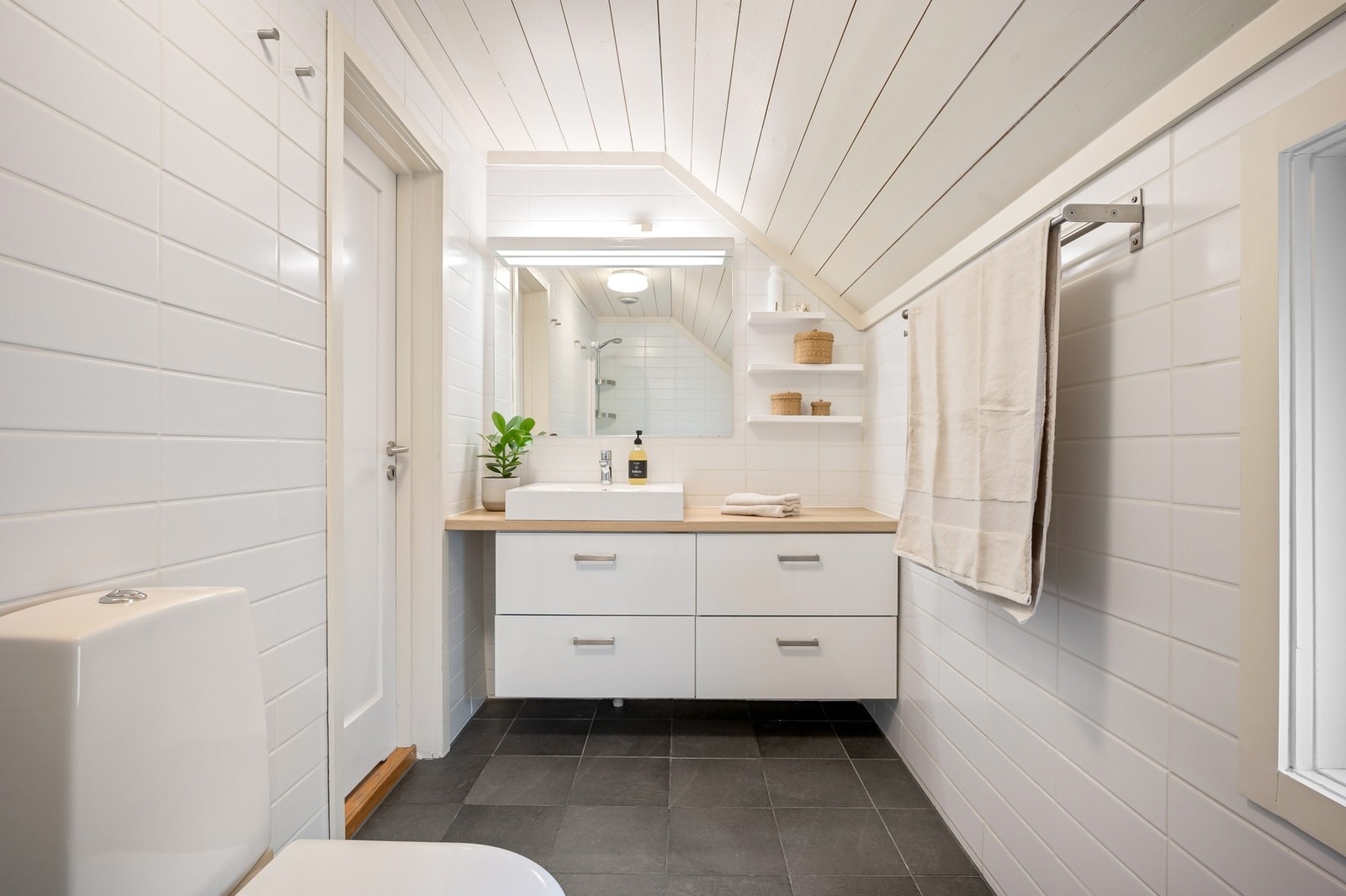 Badet i 2. etasje ble pusset opp i 2011, innredet med hvite
veggfliser og sorte gulvfliser i ulike størrelser. Et speil med belysning er plassert over en stor benkeplate med hvite, romslige skuffer og toppmontert servant. Galleribilde