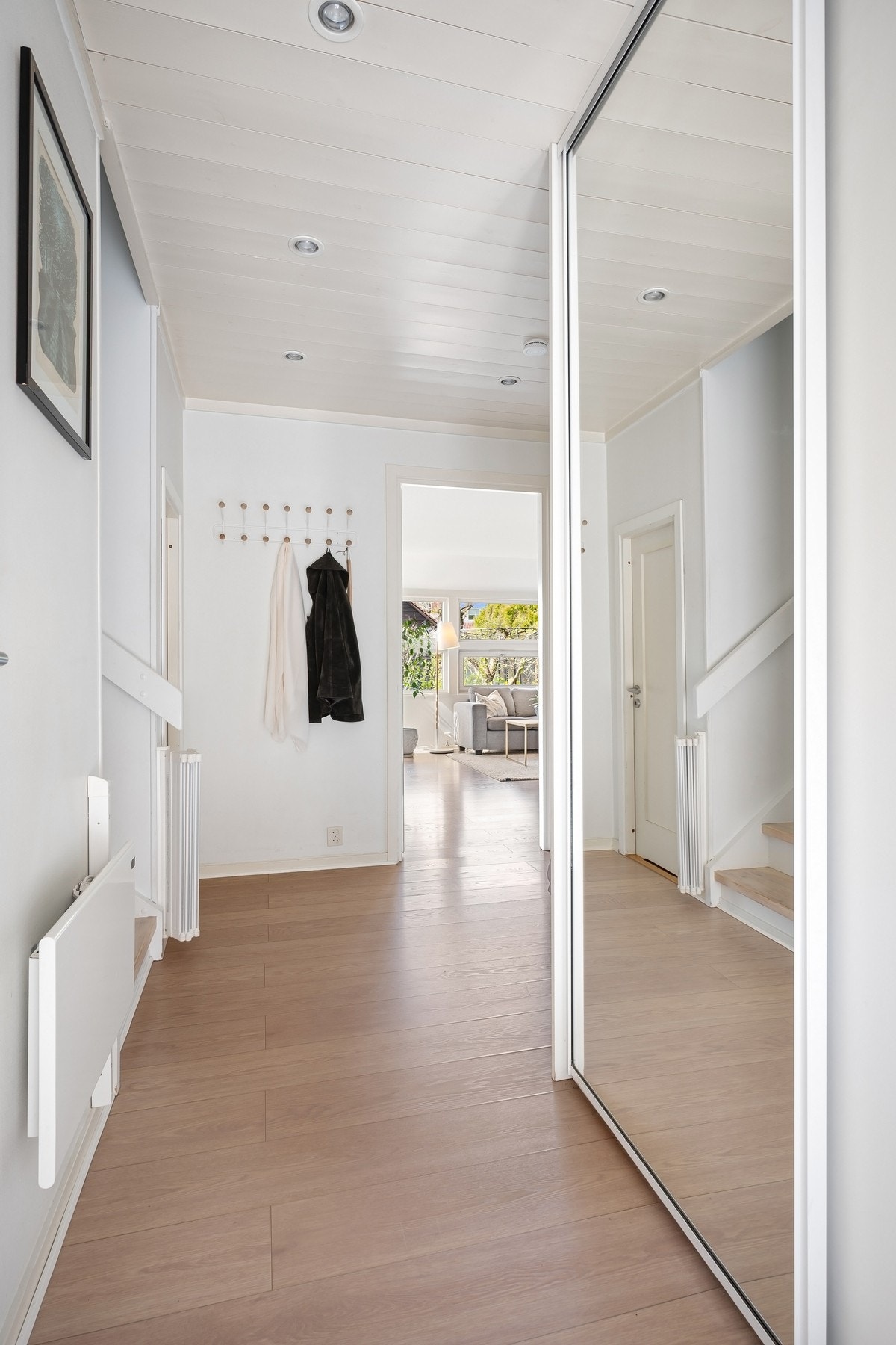 Entreen har downlights, 1-stavs laminagulv og plassbygget skyvedørsgarderobe med dels speilfronter. Gulvet fra entreen fortsetter inn i stuen og kjøkkenet for et helhetlig uttrykk. Galleribilde