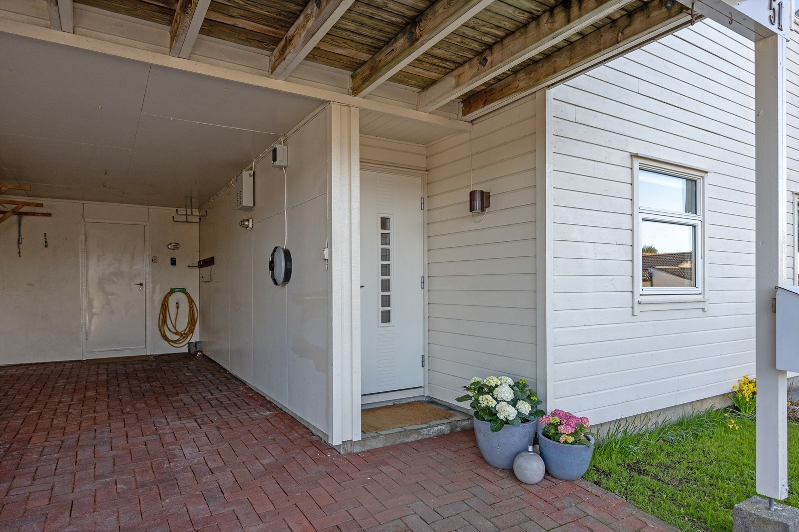 Overbygget inngangsparti og parkering i carport. Det er installert elbillader som er koblet til husets strømmåler. Galleribilde