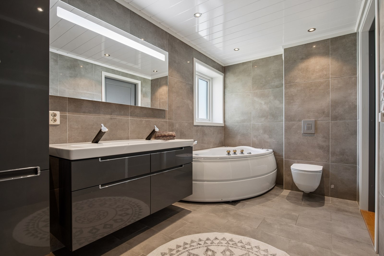 Badet i første etasje er romslig og utstyrt med både dusjnisje og boblekar for ekstra komfort. Galleribilde