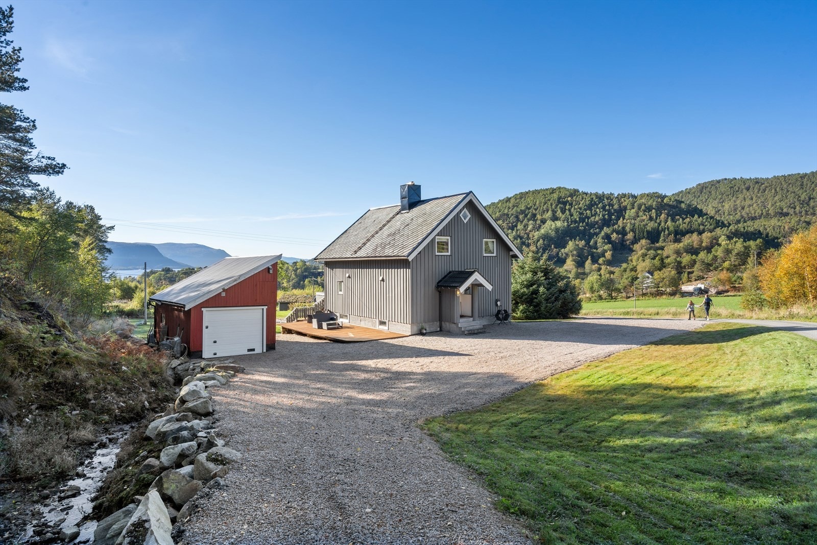 Stor og flott tomt opparbeidet med uteplasser, frodig hage med beplantning og stort uthus. Galleribilde