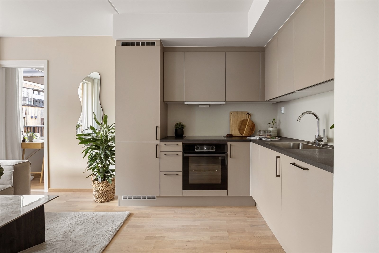 Kjøkkenet har en moderne innredning med glatte, mørke fronter og slitesterk laminat benkeplate. Det er godt med oppbevaringsplass i både over- og underskap, noe som gir en ryddig og funksjonell kjøkkenløsning. Galleribilde