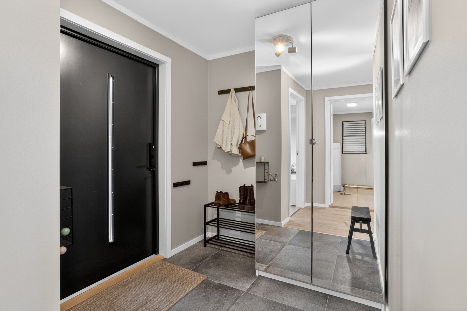 Entréen i boligens første etasje er lys, innbydende og romslig, med flislagt gulv og god plass til yttertøy og skotøy. Et praktisk garderobeskap med speildører gir god oppbevaringsplass. Galleribilde