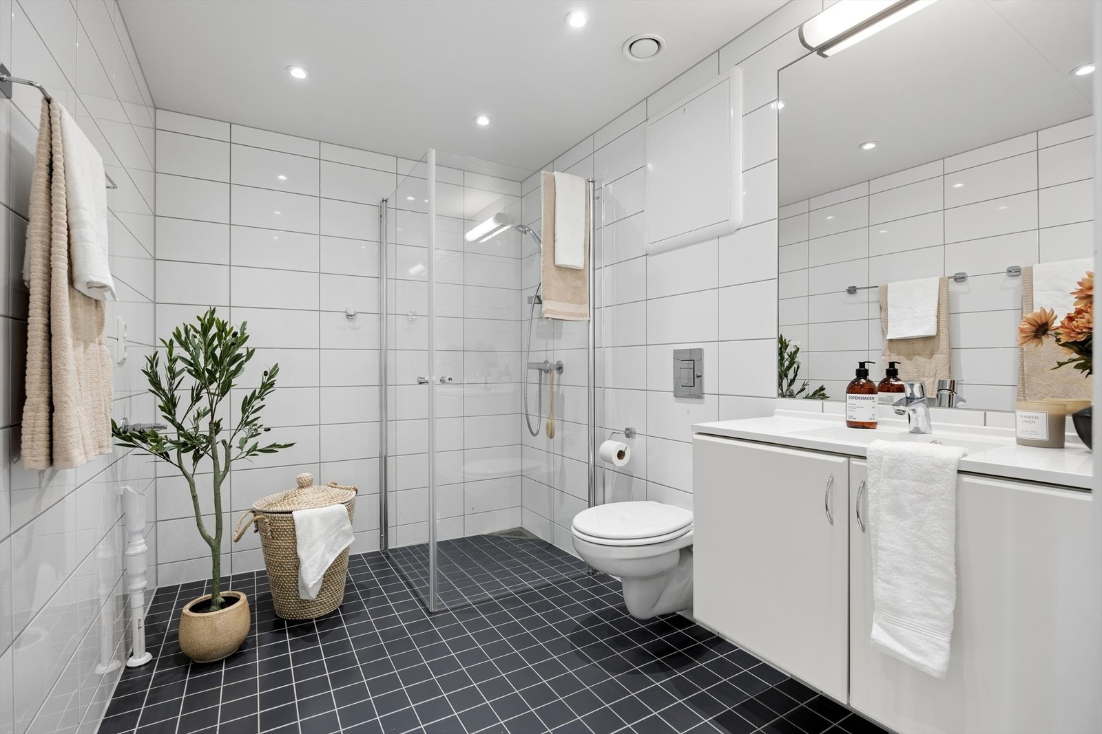 Stort flislagt bad med gulvvarme og downlights i himling. Lys innredning og praktisk dusjhjørne. Toalett og opplegg for vaskemaskin. Galleribilde