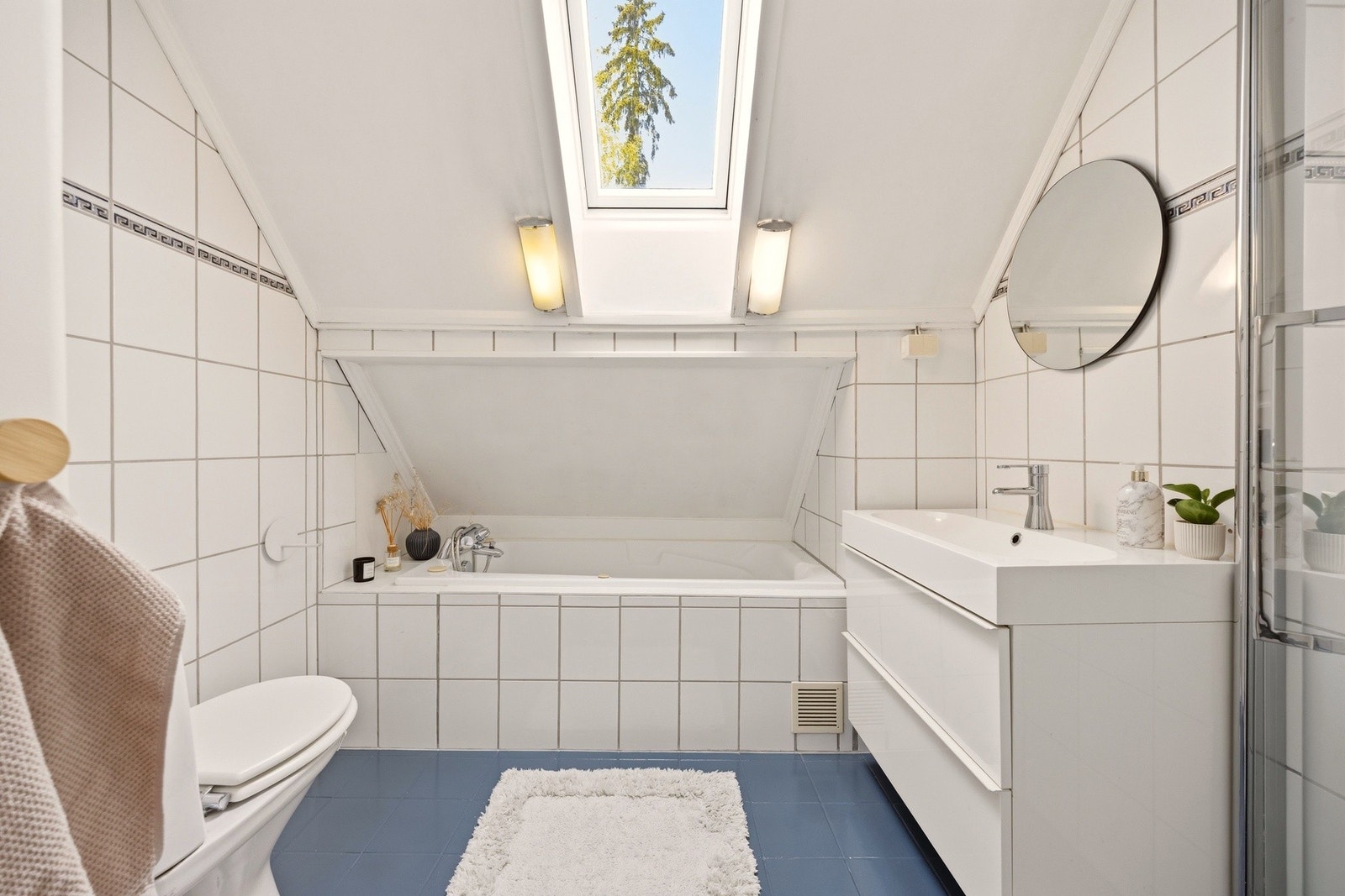Flislagt bad med dusj, badekar, toalett og servant, med godt
lysinnslipp fra takvindu. Galleribilde