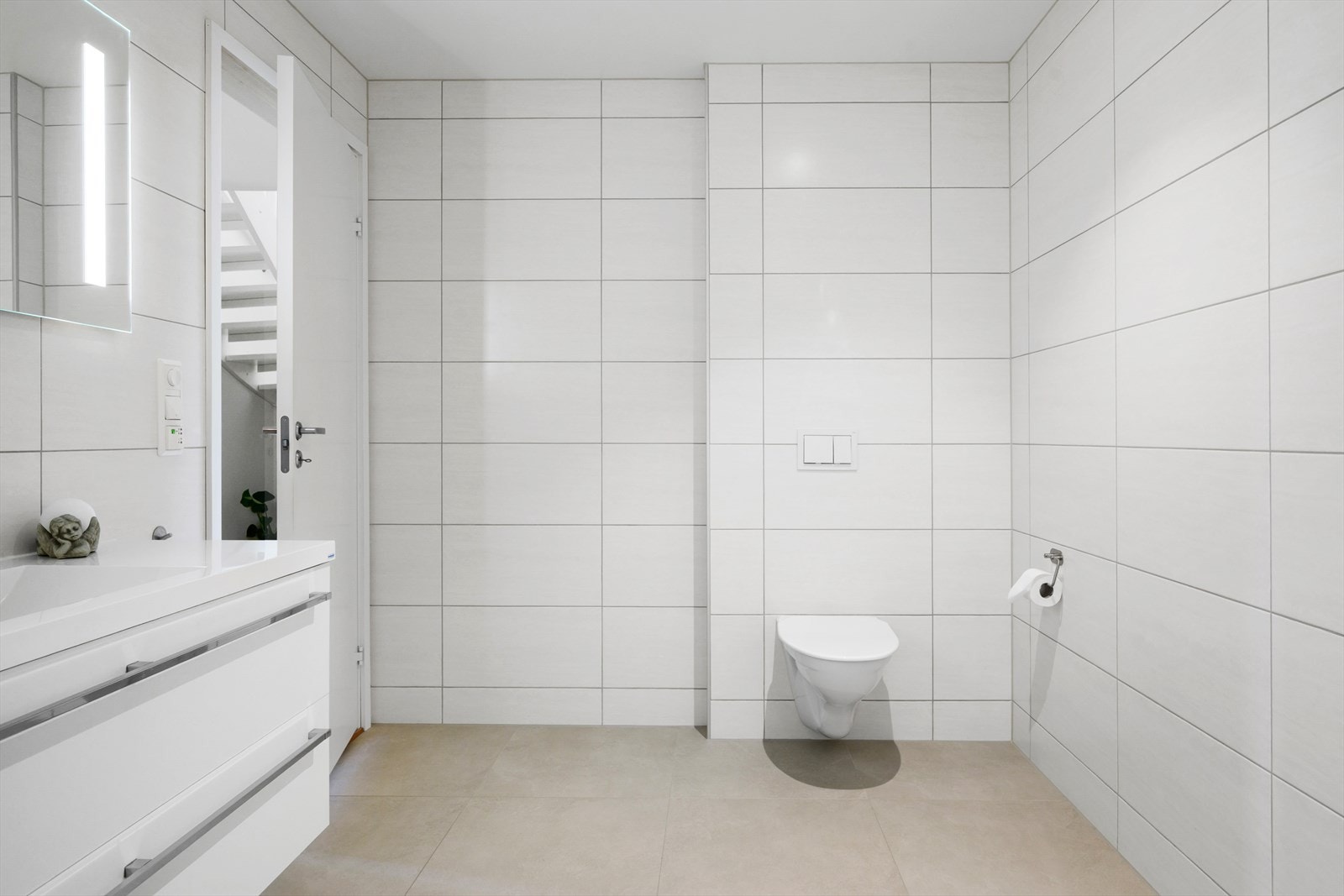 Badet har en stilren innredning med servant nedfelt i skap, speil med integrert belysning og vegghengt toalett. Galleribilde