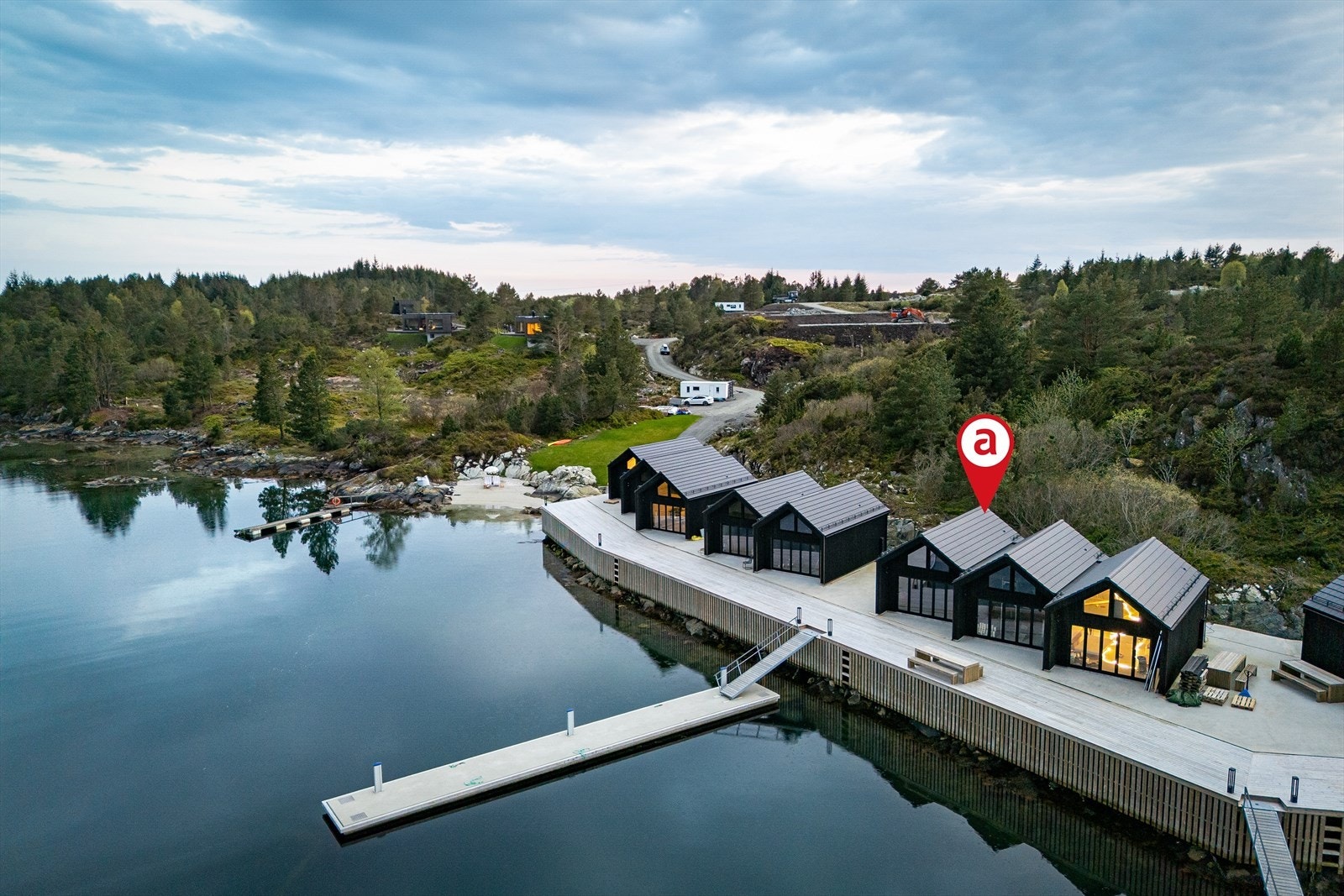 Kun 80 meter fra eiendommen har du tilgang til felles kaianlegg og felles badestrand. Her er det 12 naust med samme harmoniske design, med 100 meter kai og 42 båtplasser. Galleribilde