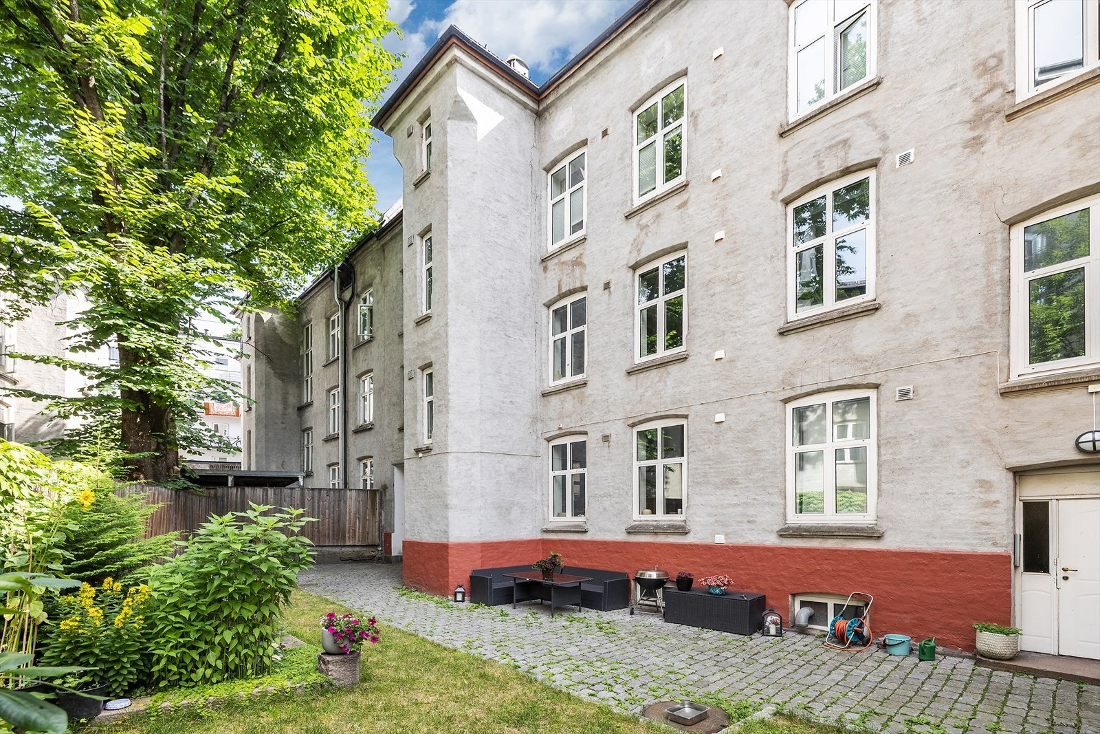 Hyggelig bakgård med beplantning, plen og sittegruppe. Galleribilde