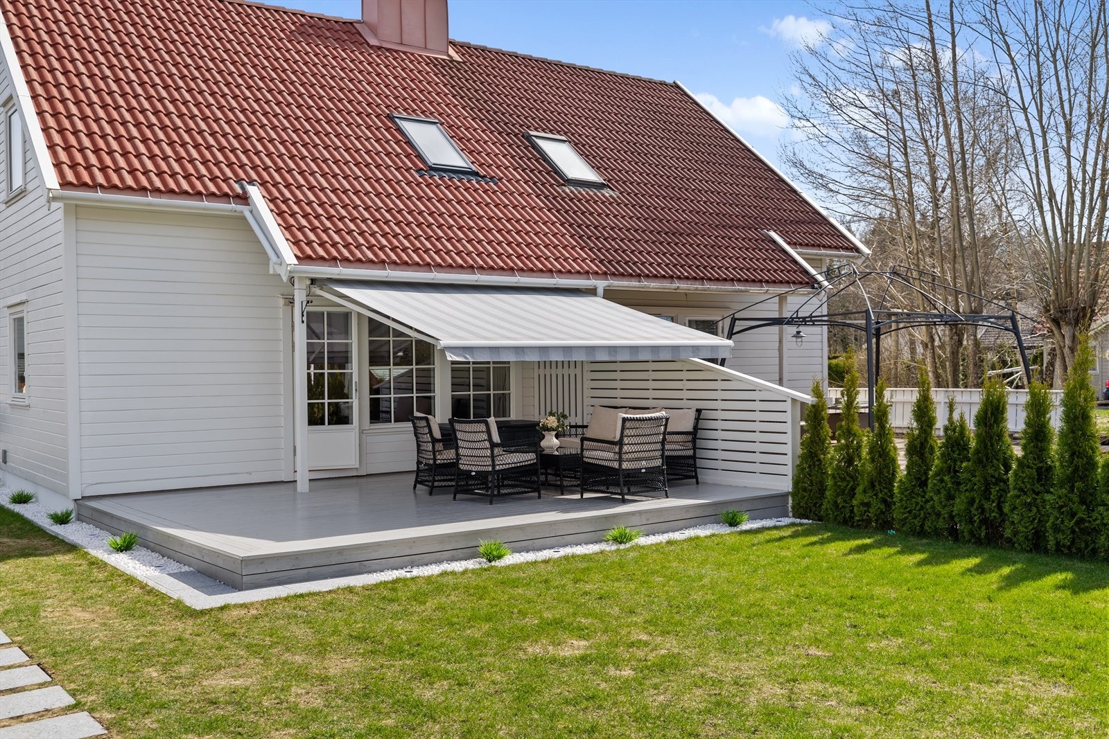 Terrassen fremstår som en naturlig forlengelse av boligen, og er utstyrt med markise som gir behagelig skygge på varme dager. Galleribilde