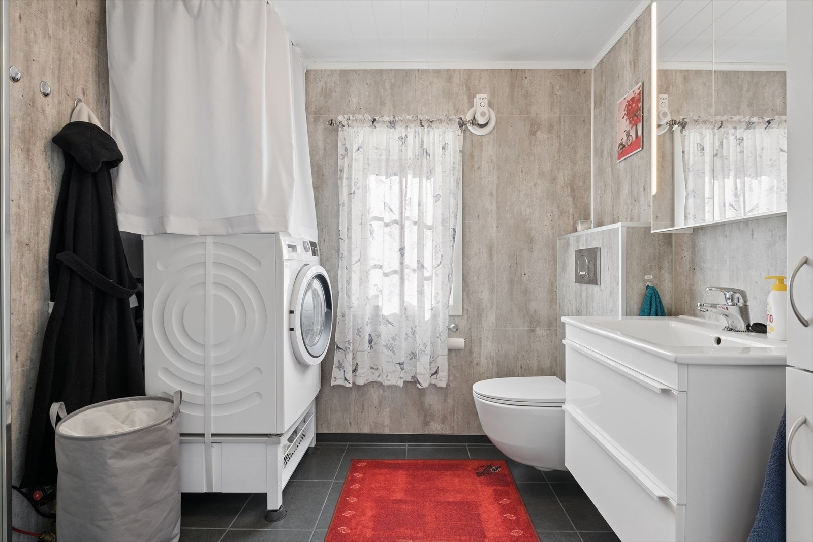 Badet er utstyrt med moderne fasiliteter, inkludert vegghengt toalett og opplegg for vaskemaskin. Galleribilde