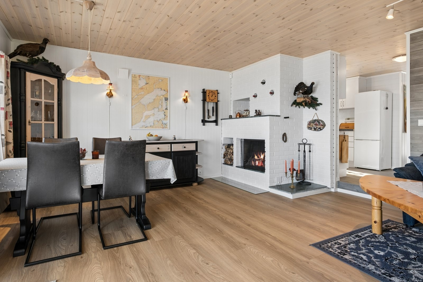 En stemningsfull peis er sentralt plassert i stuen, og suppleres av en effektiv varmepumpe for jevn temperatur. Galleribilde