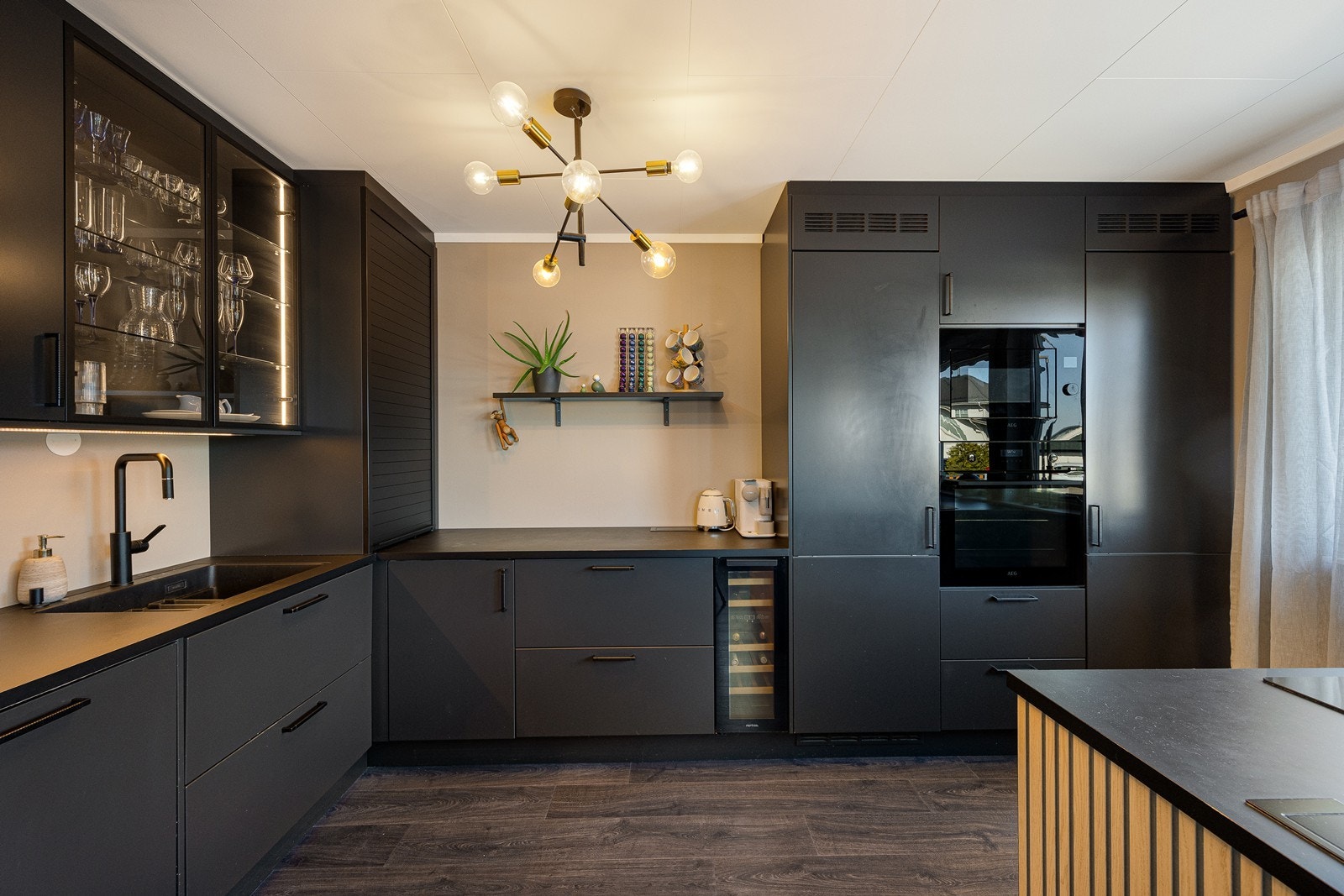 Den takhøye innredningen er fra Huseby og fremstår svært gjennomtenkt med sorte, glatte fronter, vitrinedører og sort laminatbenkeplate med planlimt, sort kum. Galleribilde