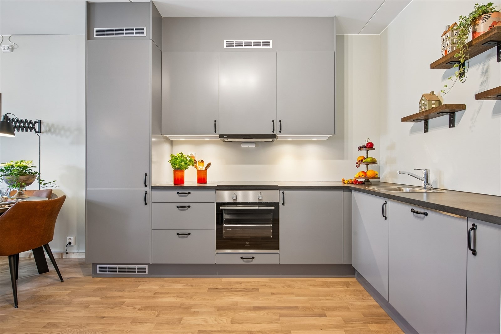 Moderne kjøkkeninnredningen med glatte fronter, laminatbenkeplate og integrert komfyr, platetopp, oppvaskmaskin og kjøl/frys. Galleribilde