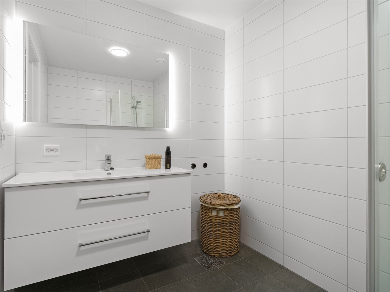 Også badet i underetasjen er helfliset og utstyrt med gulvvarme, vegghengt toalett og dusjhjørne med innfellbare glassdører. Galleribilde