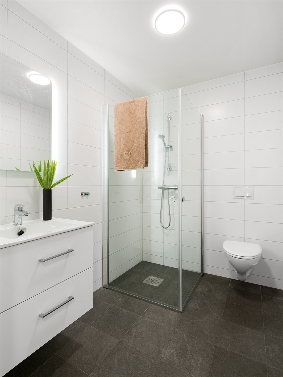 Badet i første etasje har fliser på gulv og vegger, elektrisk gulvvarme og vegghengt toalett. Galleribilde