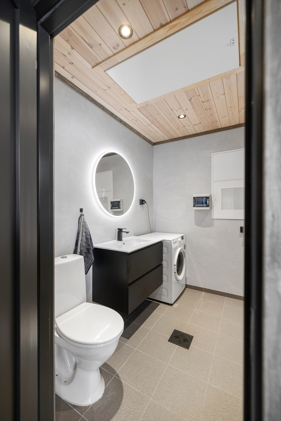 Et praktisk vaskerom som også fungerer som gjestetoalett, med WC, servant og opplegg for vaskemaskin. Galleribilde