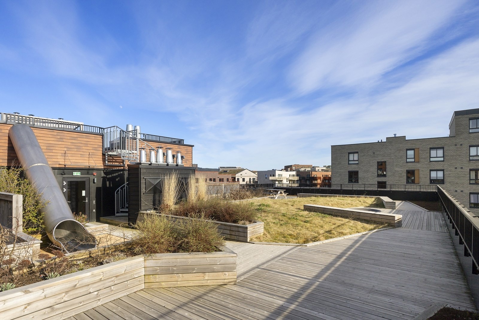 Felles takterrasse i samme etasje som boligen med sittegrupper, beplantning og åpne gangsoner Galleribilde