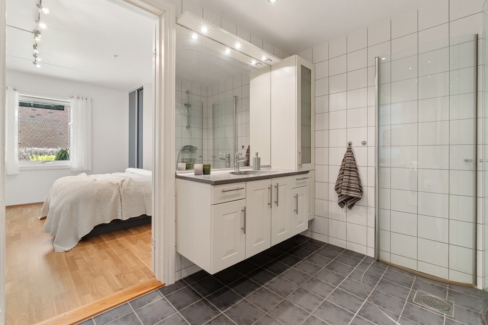 Rommet er for øvrig belyst med innfelte downlights i himling. Badet har også en innfliset nisje med opplegg for vaskemaskin og tørketrommel i søyle. Badet har adkomst fra både gang og hovedsoverom. Galleribilde