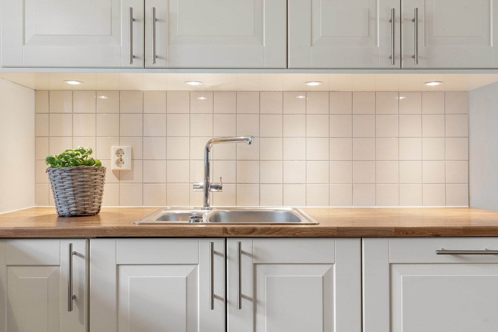Over benkeplate er det delikate, beige veggfliser og belysning. Galleribilde