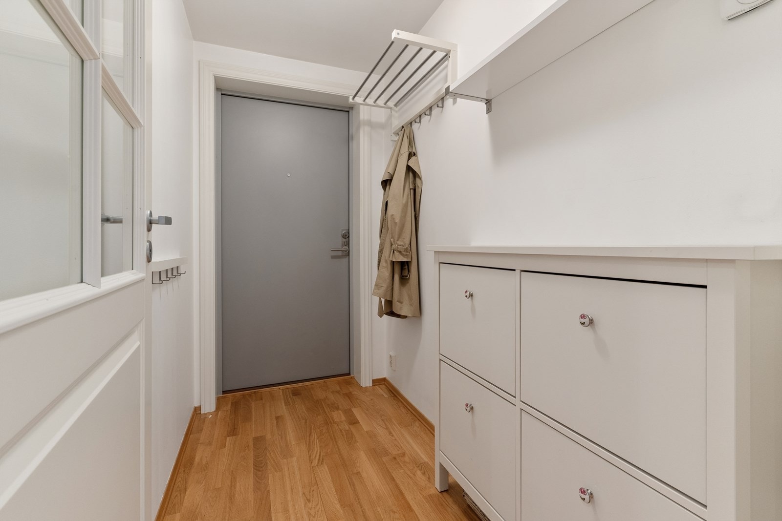 Entreen gir et godt førsteinntrykk av leiligheten og er praktisk innredet med blant annet åpen garderobeløsning og skoskap. Fra entreen er det vitrinedør til gang med downlights belysning og skyvedørsgarderobe med speilfronter. Galleribilde