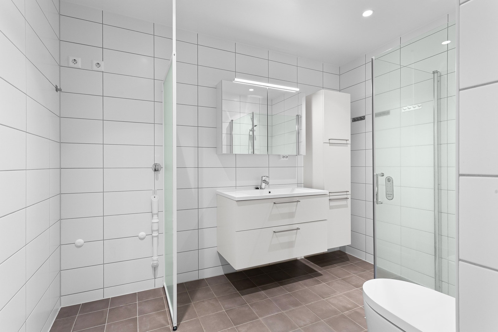 Badet har dusjhjørne med innfellbare glassdører, dusjtoalett og opplegg for vaskemaskin. Galleribilde