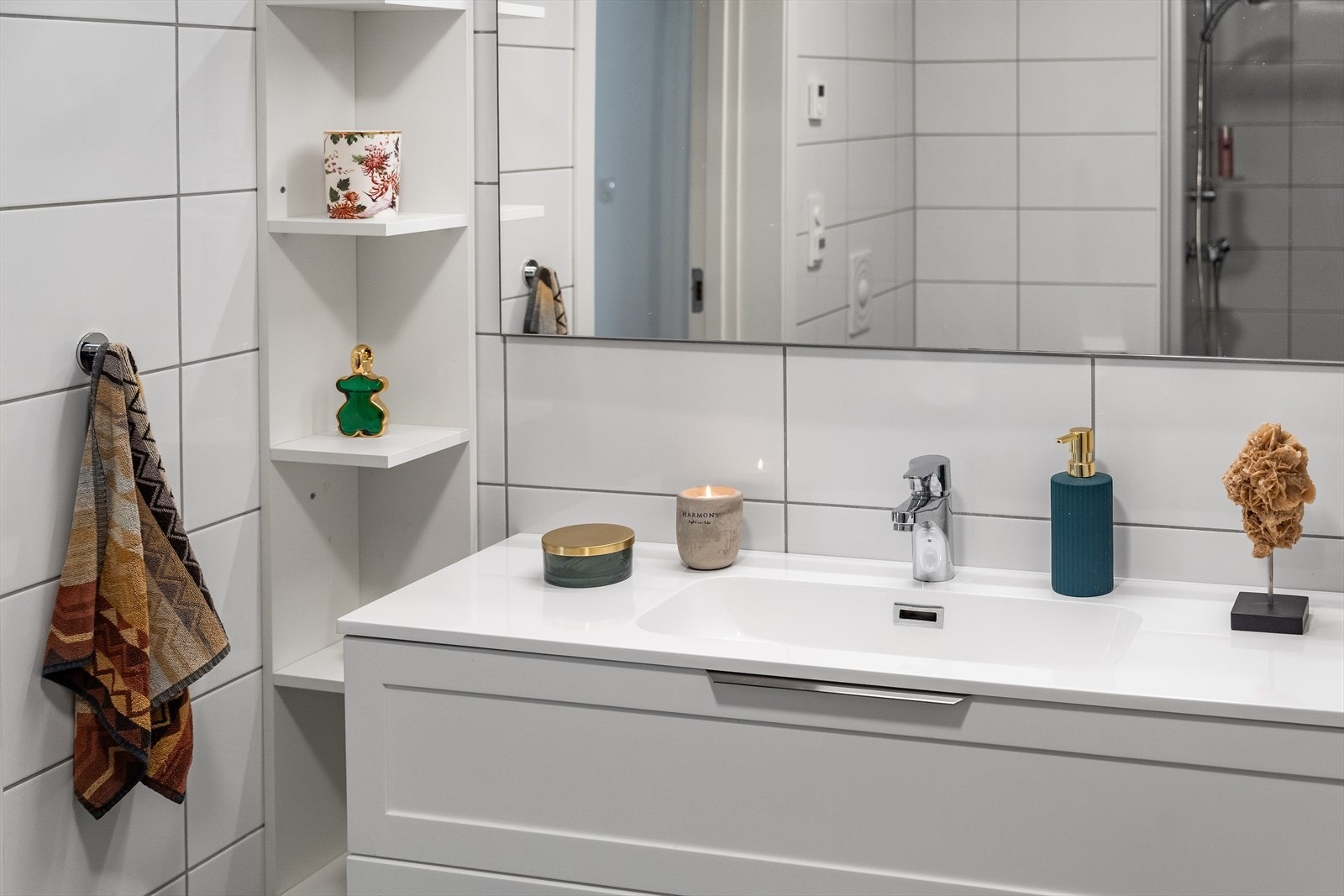 Badet er innredet med med hvit baderomsinnredning og hvit vask fra 2025, hyller på vegg og walk-in-dusj med glassvegg. Galleribilde