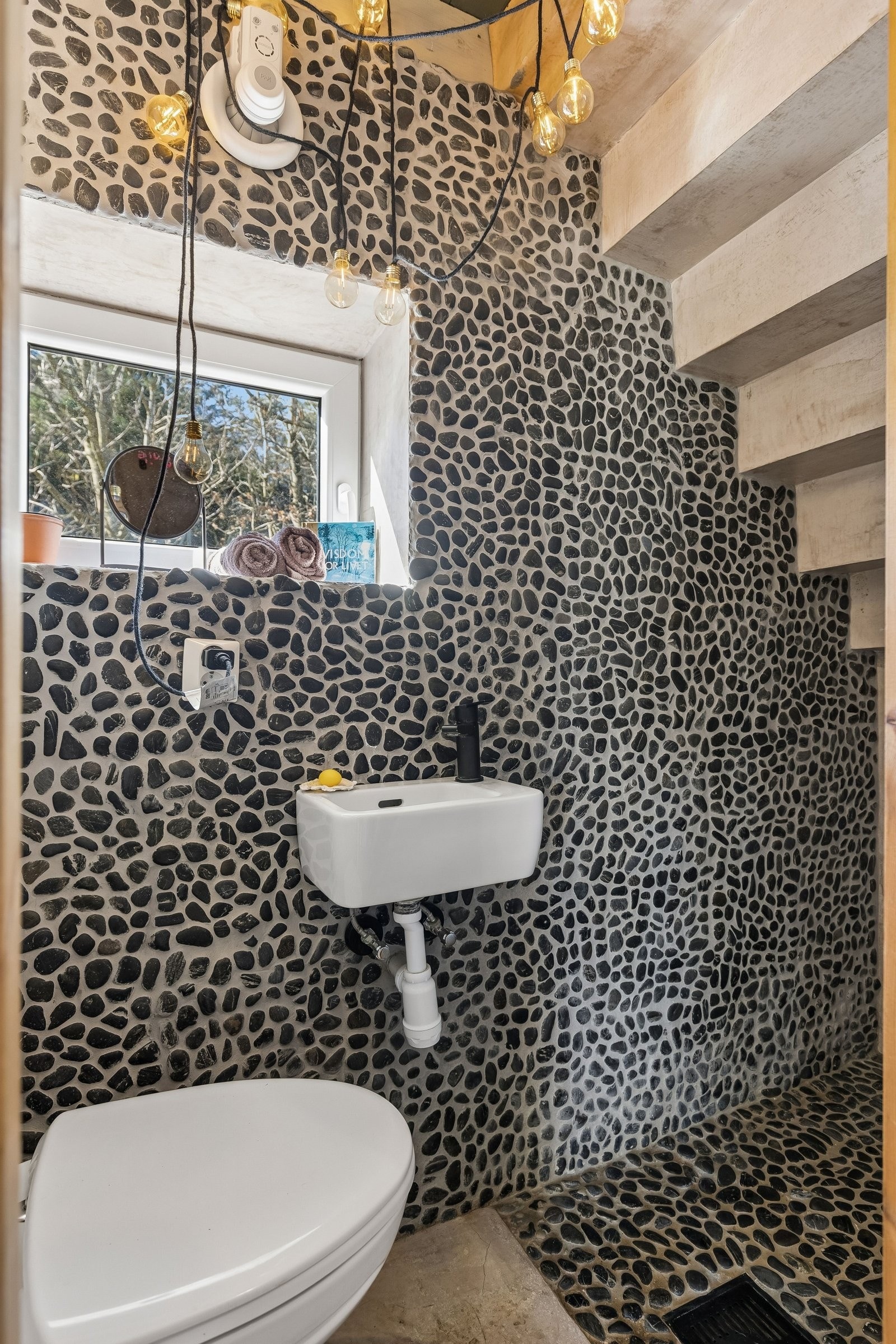 Gjestebad med dusj i 1.etasje. Rullestein på vegg og gulv i dusj, mikrosement likt som hovedbadet. Galleribilde