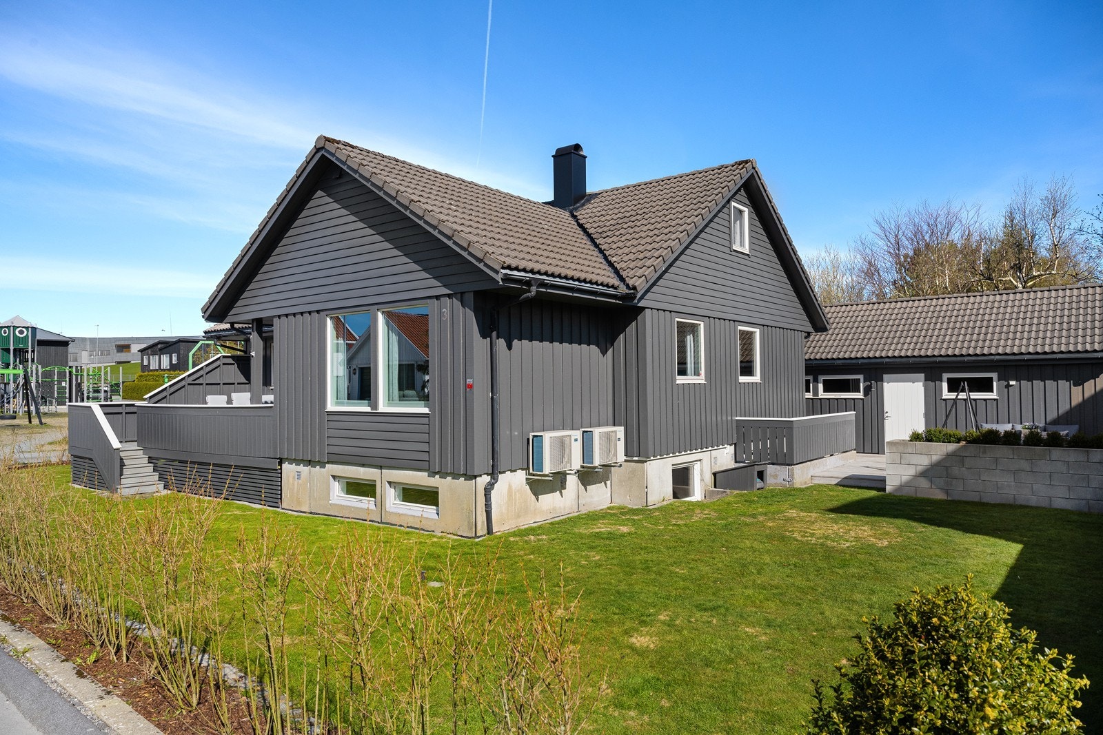 Tomten er pent opparbeidet med gressplen og diverse beplantning. Galleribilde