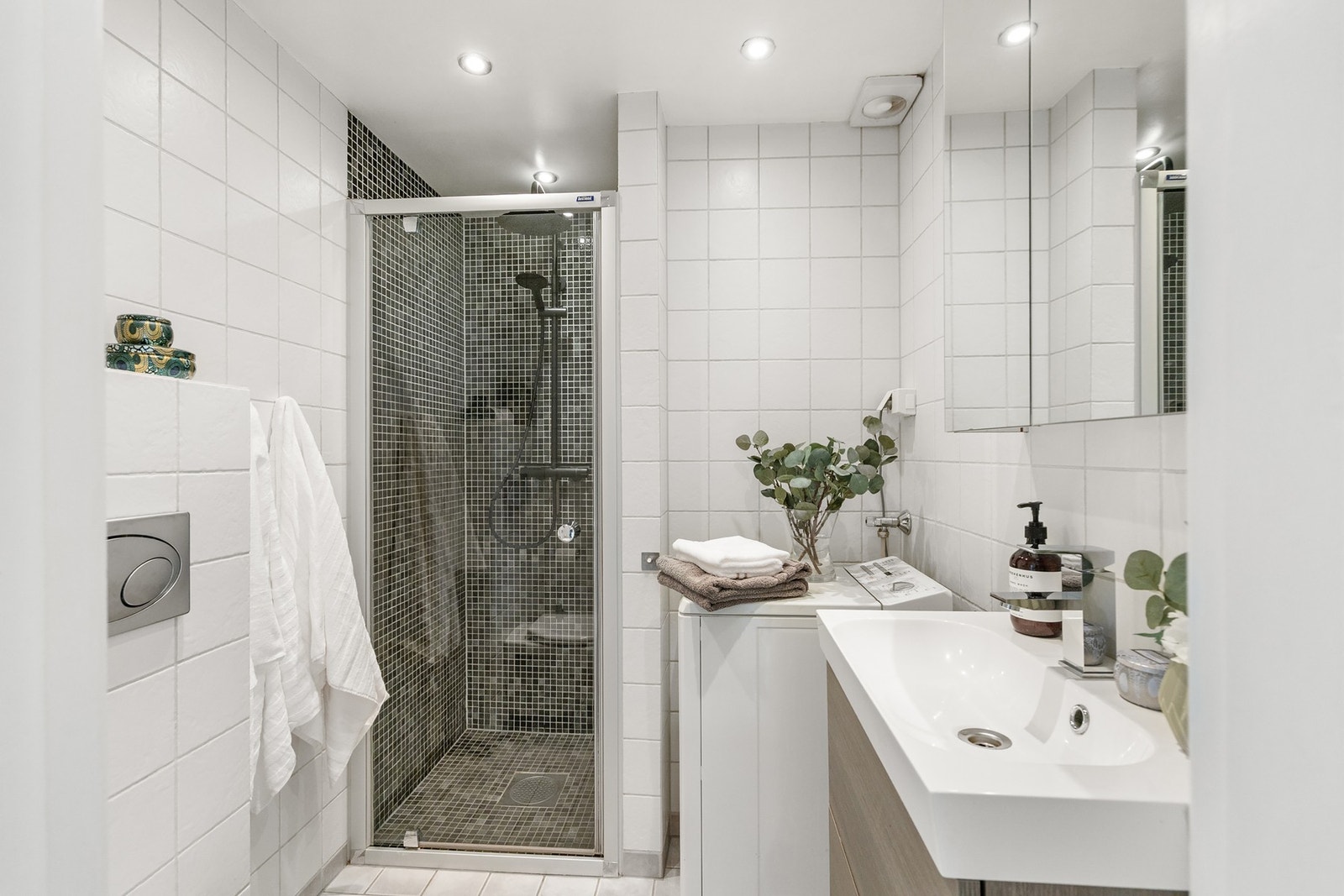 Badet er innredet med servantskap med nedfelt servant, veggskap med speildører, vegghengt toalett og dusjsone. Galleribilde