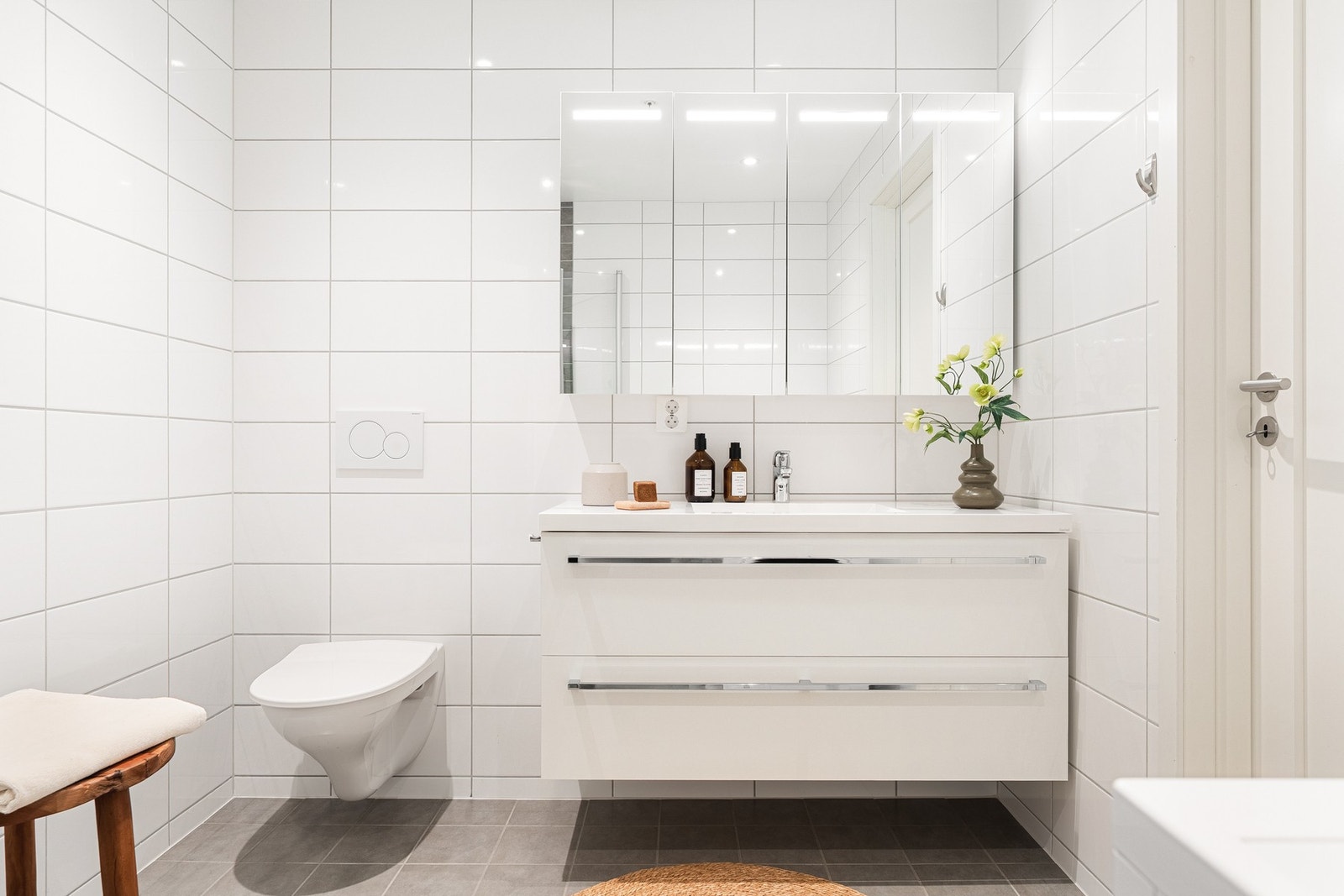 Badet er innredet med vegghengt toalett, servant med innredning, speilskap, dusjhjørne med glassdører og opplegg for vaskemaskin. Galleribilde
