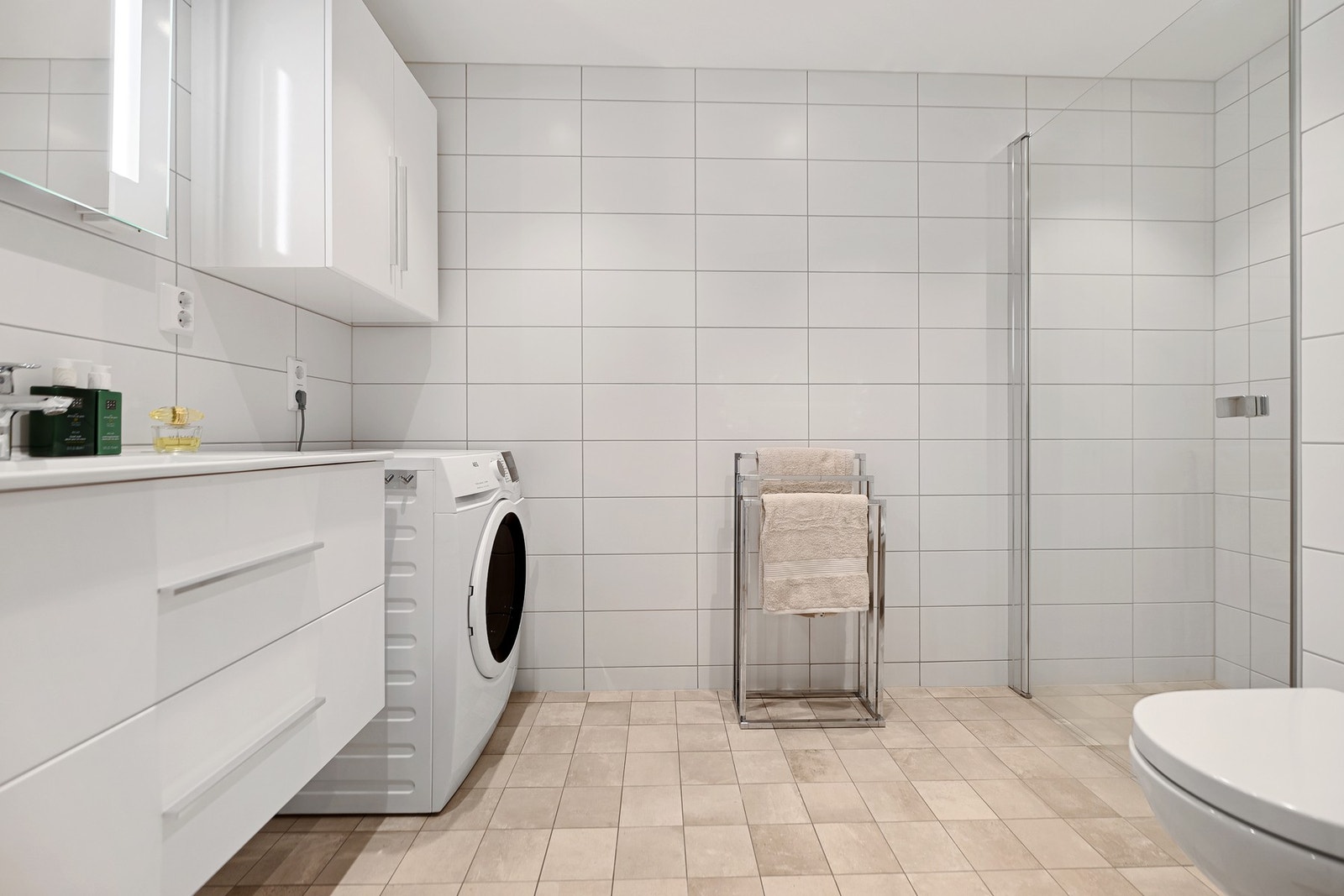 Badet er innredet med servantskap, speil med lys, vegghengt wc, opplegg for vaskemaskin og dusjnisje. Galleribilde