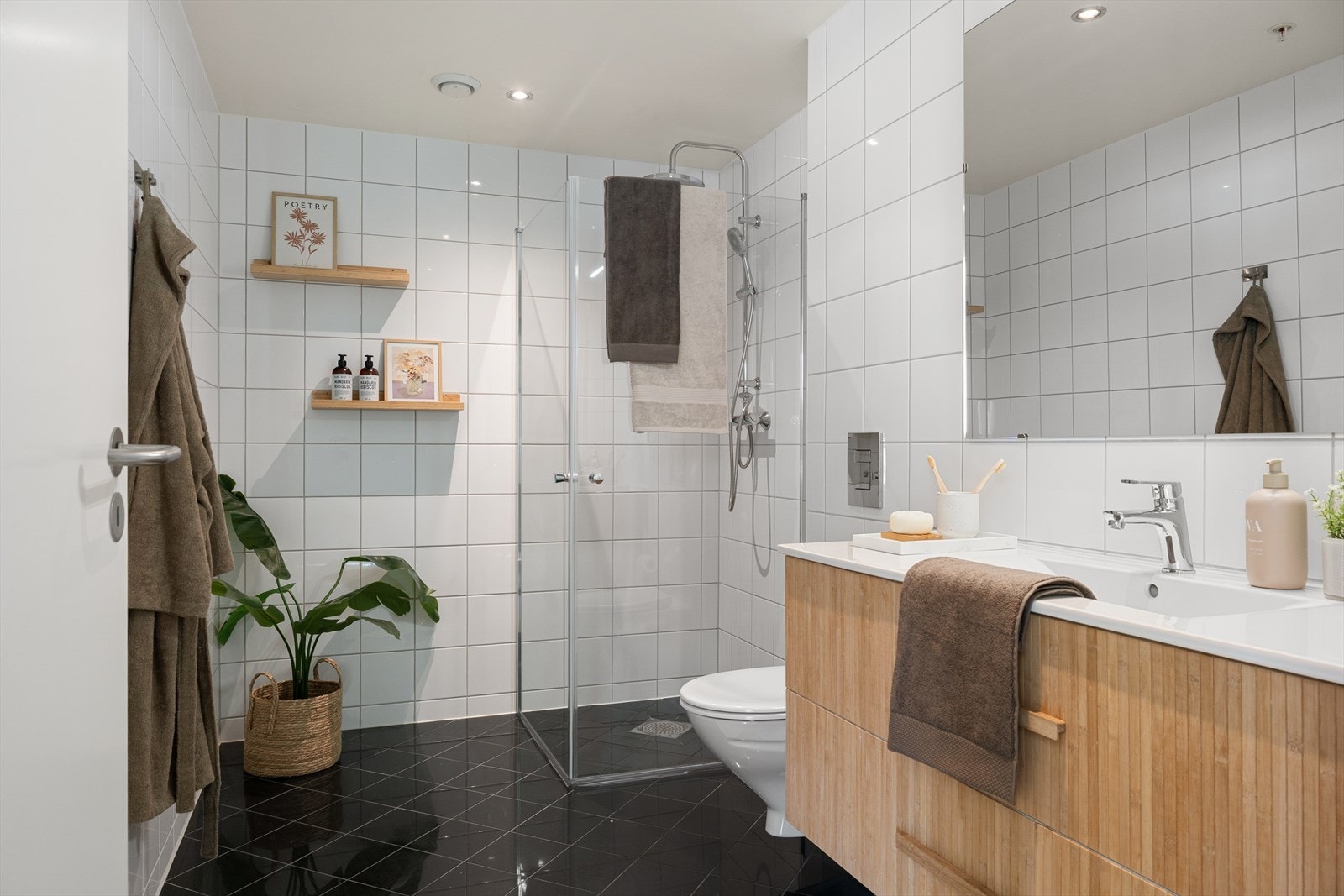 Badet er helfliset med sorte fliser på gulv og hvite fliser på veggene. Galleribilde