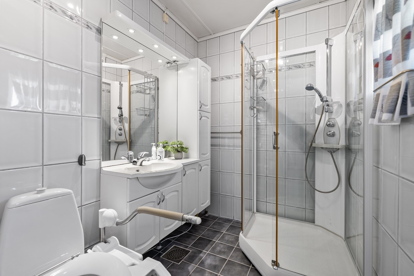 Badet fremstår som funksjonelt og praktisk innredet med flislagte vegger og gulv. I gulvet er det elektriske varmekabler som sørger for god komfort året rundt. Himlingen består av malte plater som gir et lyst og helhetlig preg. Galleribilde