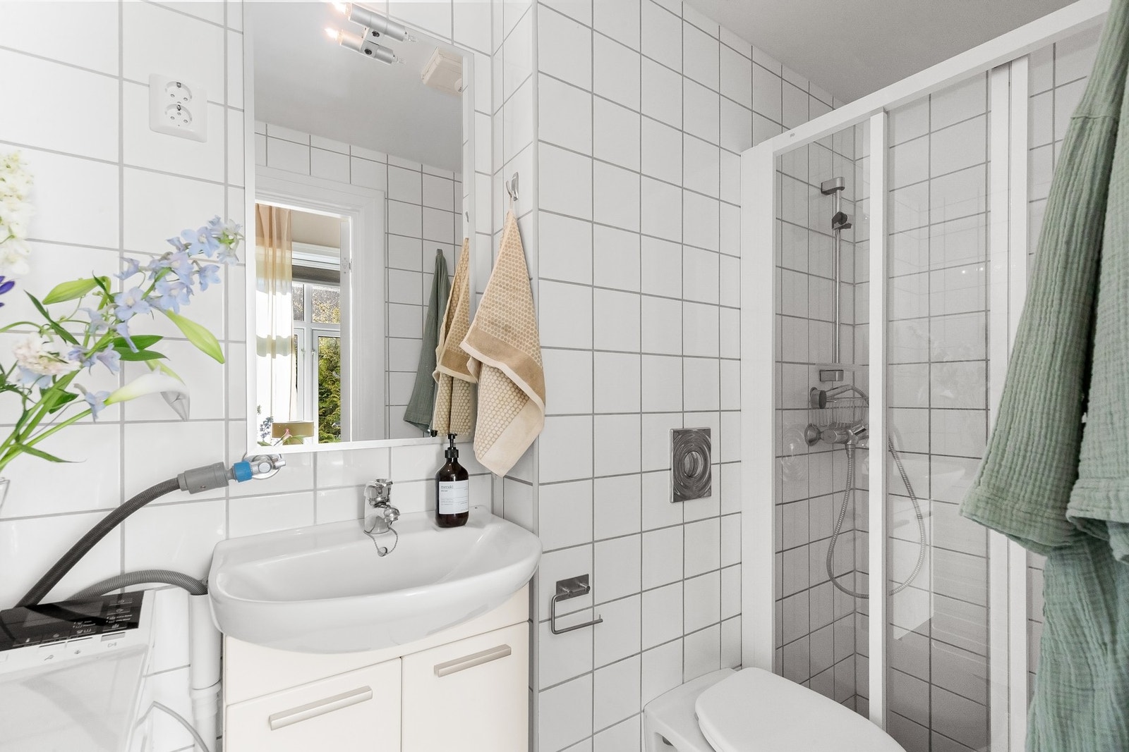 Tidløst, flislagt bad med varmekabler og opplegg for vaskemaskin. Galleribilde