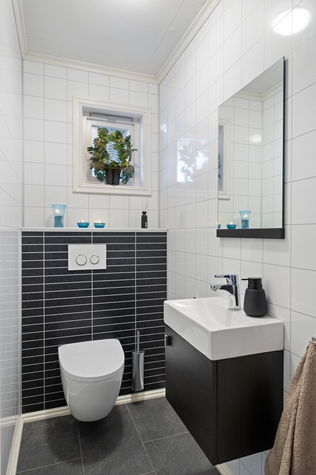 Flislagte vegger og gulv gir et stilrent uttrykk på badet. Vegghengt toalett og moderne servantløsning gir enkel rengjøring. Galleribilde