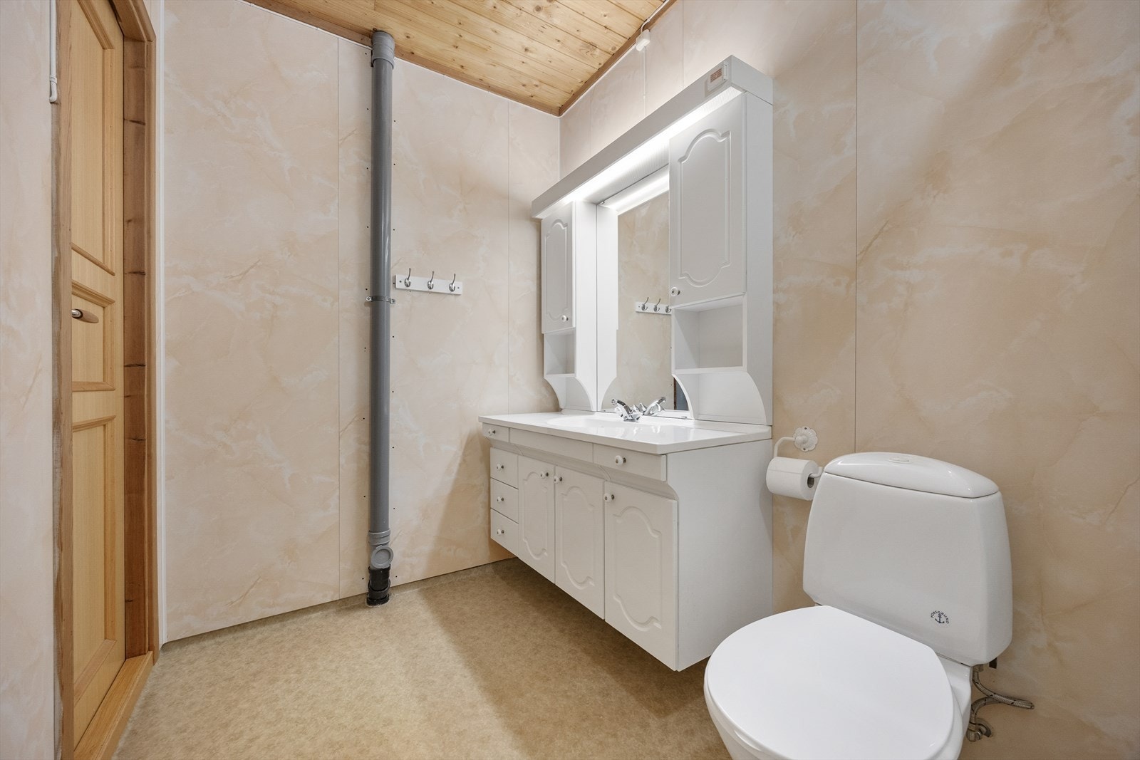 Badet i underetasjen har varmekabler, plater på vegg og vinylbelegg på gulvet. Innredningen består av en heldekkende servant med hvite underskap, to veggskap i samme stil og et stort speil med tilhørende lys. Galleribilde