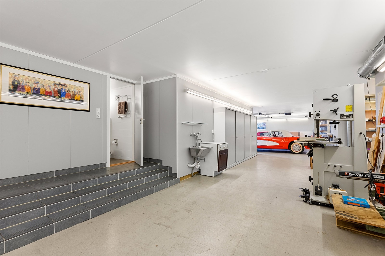 Det integrerte garasjeanlegget fremstår som et gjennomført og funksjonelt område med epoxymalt gulv, vannbåren gulvvarme, balansert ventilasjon, verkstedløsning og eget bad. Galleribilde