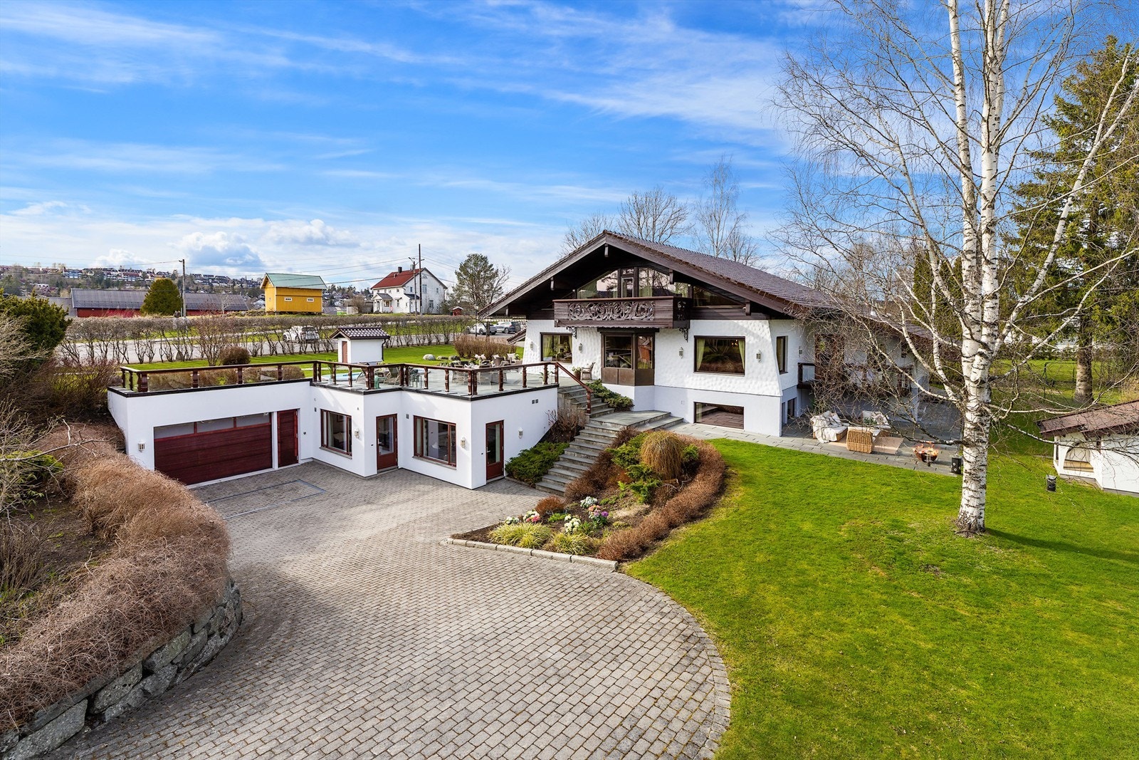 Eiendommen ligger tilbaketrukket på en solrik og parkmessig opparbeidet tomt, hvor frodig beplantning, hellelagte stier og gjennomført utebelysning skaper en harmonisk og representativ ramme. Galleribilde