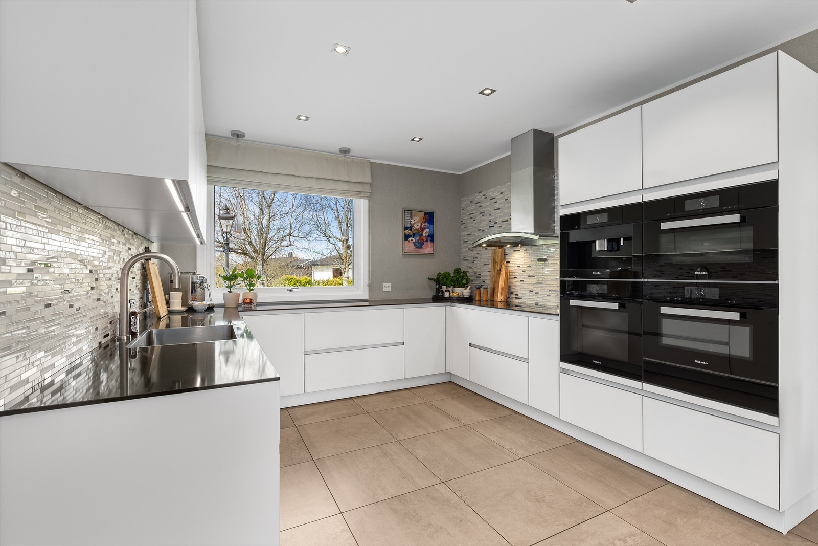 Innredning fra Next125 med glatte fronter og benkeplate i Silverstone Silestone Carbono kombineres med integrerte hvitevarer fra Miele og Gaggenau. Galleribilde