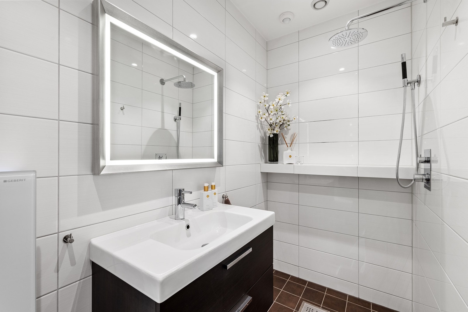Badet i første etasje ligger i direkte tilknytning til hallen og fremstår stilrent med flislagte overflater, gulvvarme og moderne innredning med heldekkende servant, integrert belysning og regnfallsdusj. Galleribilde