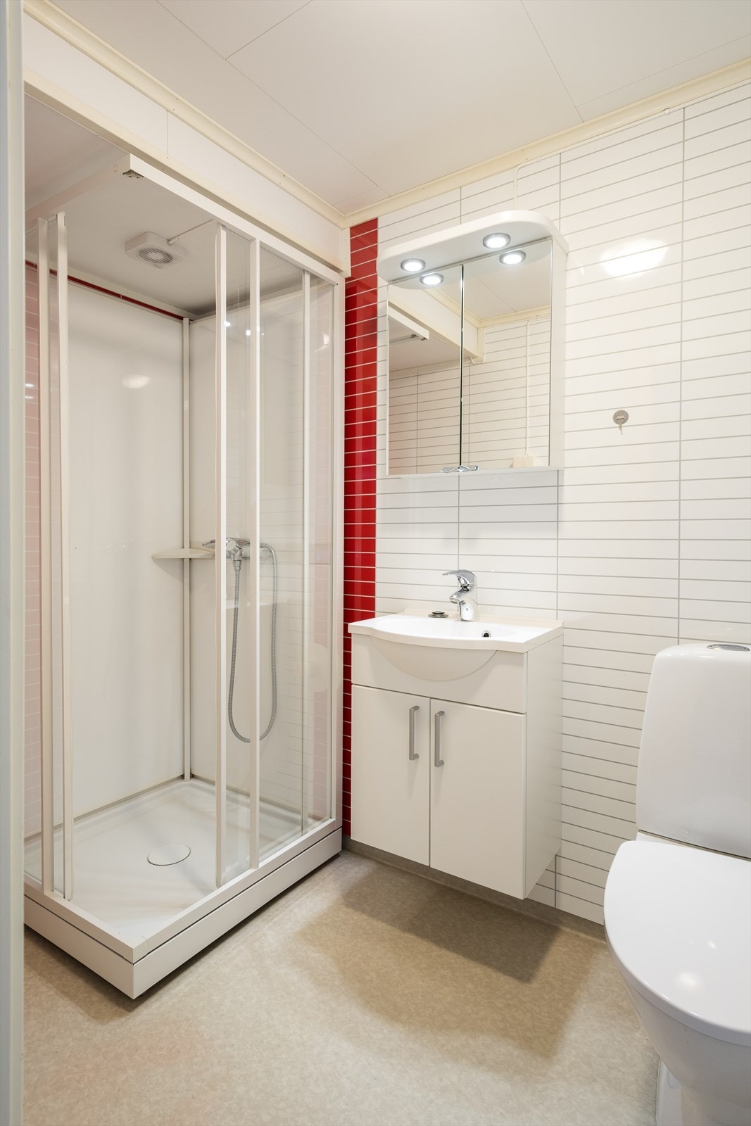 Badet er innredet med toalett, dusjkabinett og våtromsplater. Galleribilde