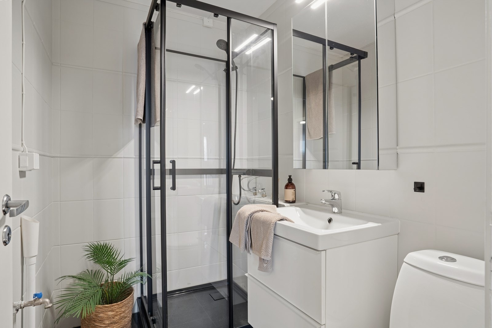 Flislagt bad utstyrt med blant annet dusjkabinett, opplegg for vaskemaskin, baderomsinnredning og toalett. Galleribilde