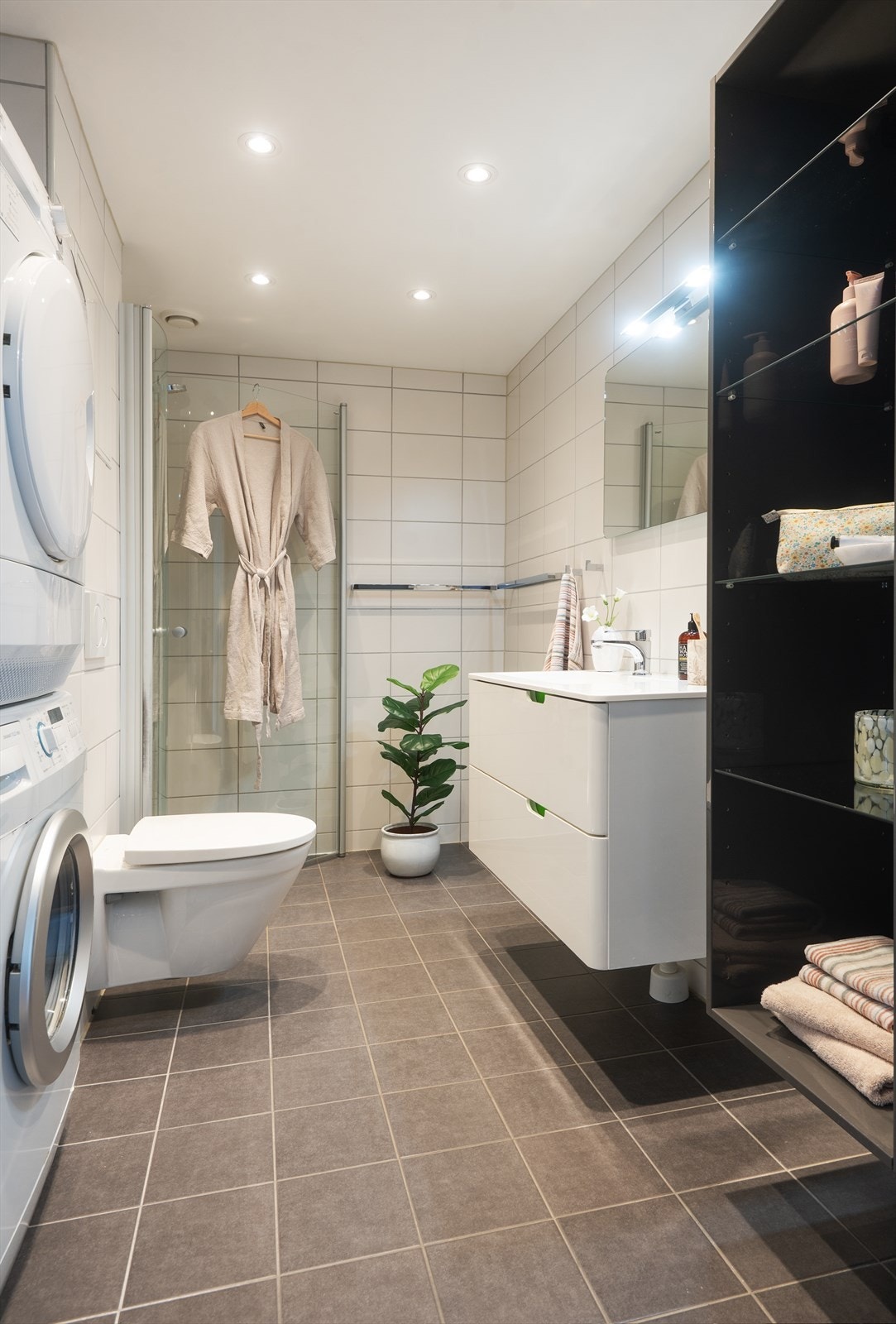 Badet er utstyrt med vegghengt toalett, dusjhjørne med glassdører og har opplegg for vaskemaskin og tørketrommel. Galleribilde
