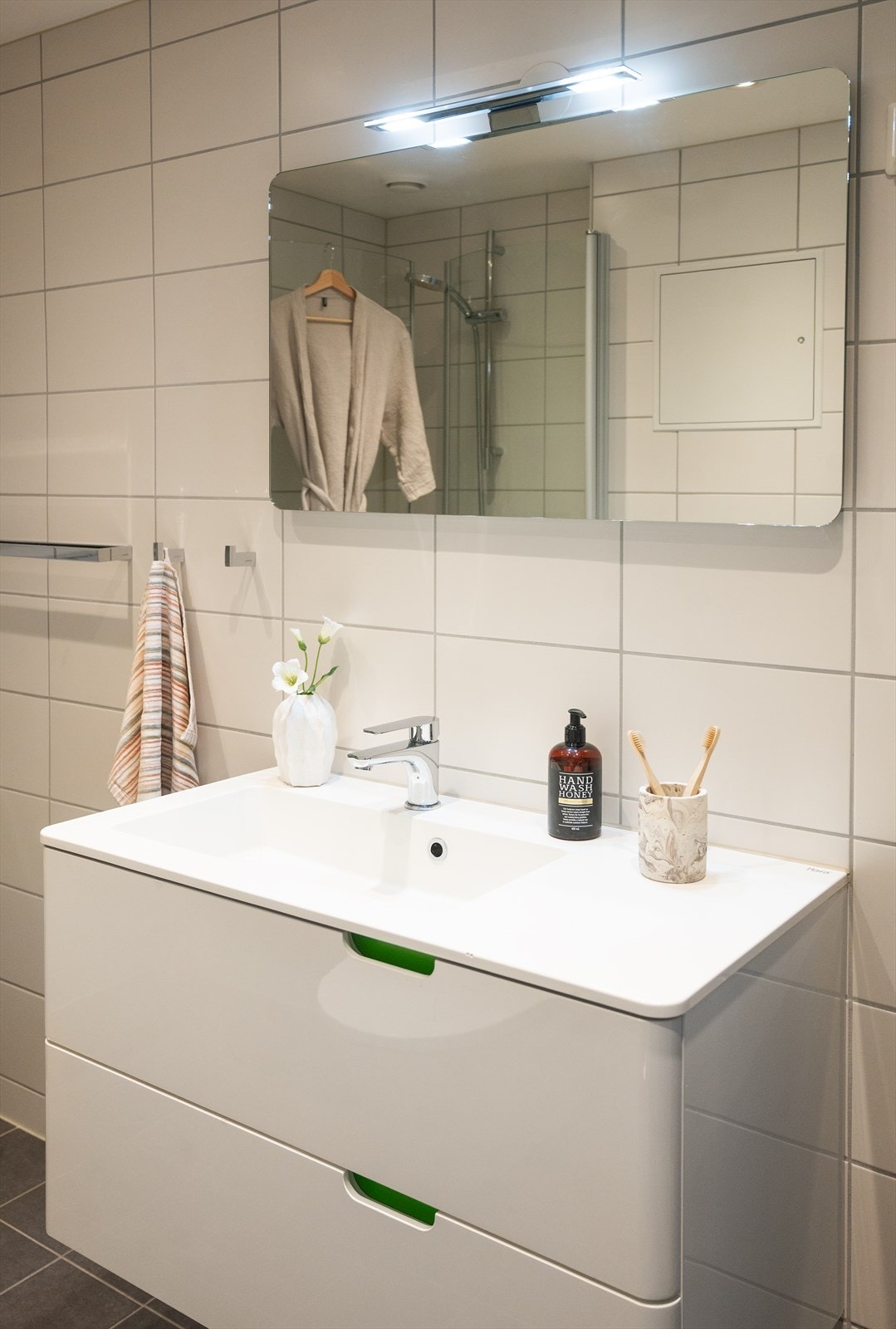 Servantinnredning med gode oppbevaringsmuligheter og speil med overlys. Galleribilde