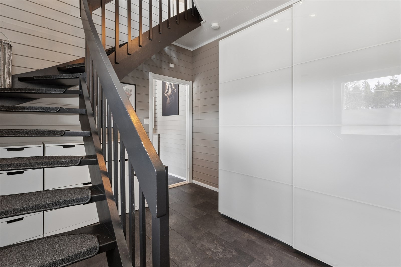 Videre innover i gangen finnes en stor skyvedørsgarderobe. God plass til kommoder under trappen Galleribilde