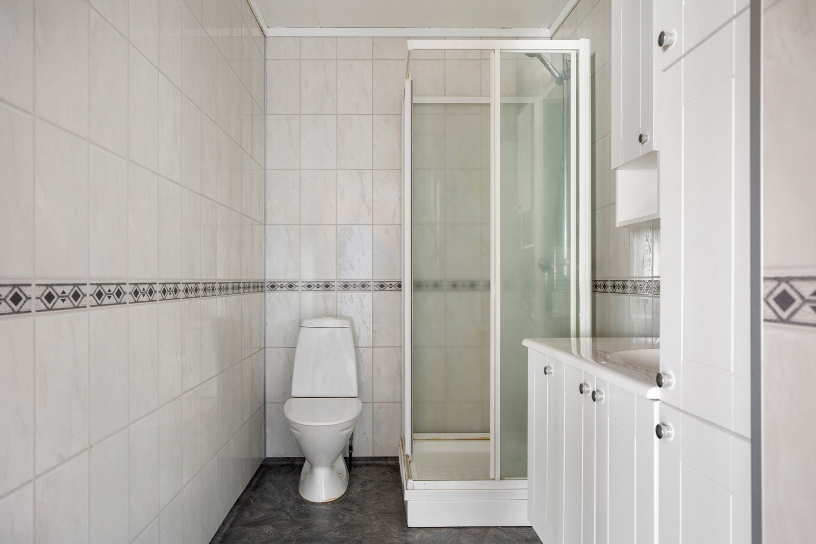 Badet i første etasje er innredet med dusjkabinett, toalett og servantseksjon. Veggene har baderomspanel og gulvet har belegg. Galleribilde