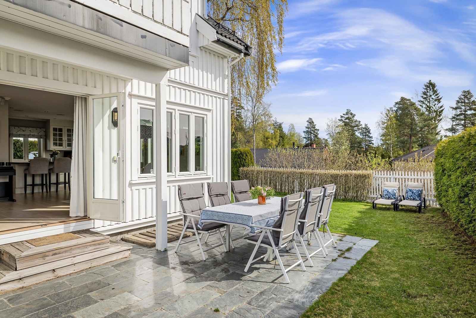 Stor terrasseplatting med skiferflis, bidrar til en bruksvennlig uteplass med plass til både spisebordet og lounge gruppe. Galleribilde