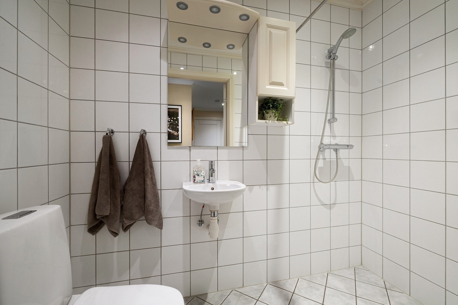 Baderom i under etasjen. Badet er utstyrt med toalett, servant og dusj. Mekanisk ventilasjon. Galleribilde