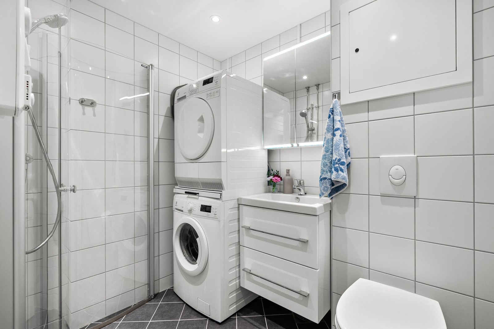 Flislagt baderom, med varme i gulv og downlights i himling. Badet har moderne baderomsmøblement; servantskap med heldekkende servant og tilhørende speilskap med lysarmatur over servant. Galleribilde