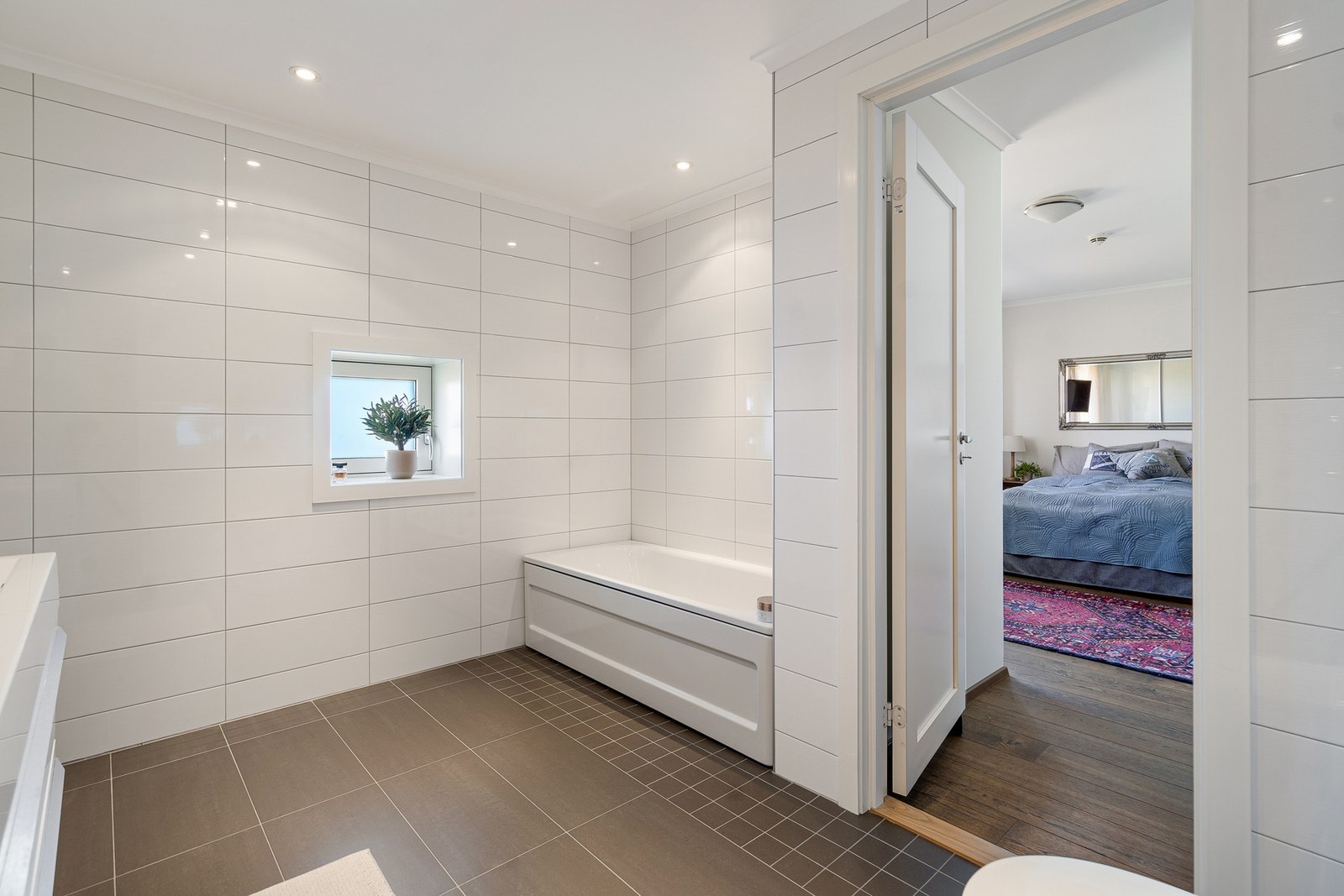 Hovedbadet er tilknyttet hovedsoverommet og holder en gjennomgående god standard. Badet er flislagt med lyse vegger og mørkere gulvfliser med gulvvarme. Galleribilde
